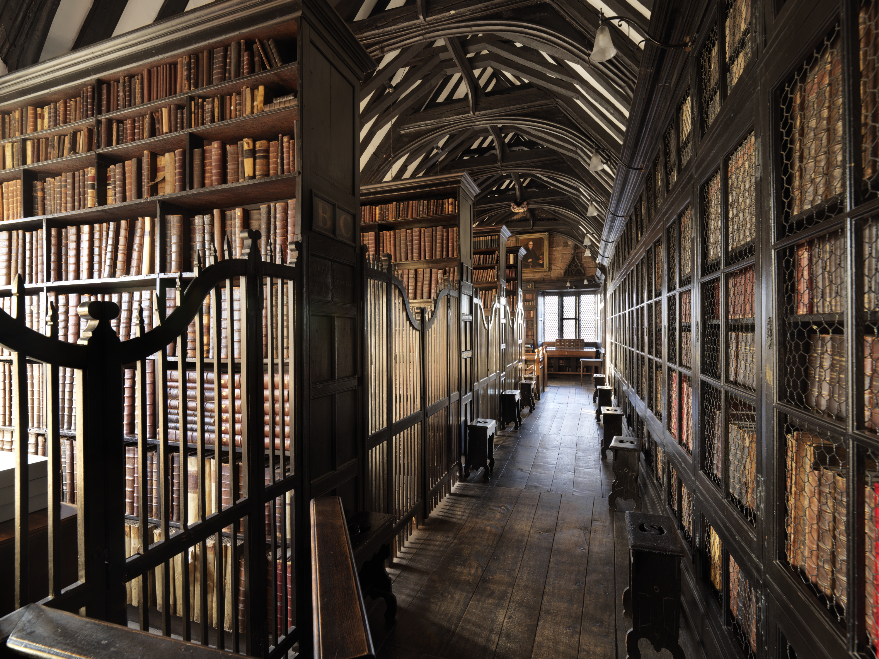 Interior view of an old library, looking along a wood-floored corridor line